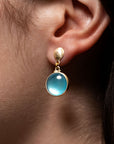 Blue topaz in sterling silver and button top earrings modeled on an ear.
