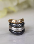Stack of five rings with different designs and colors on a light background