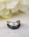 silver and black pair of rings stacked together on a blurred background