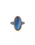 A hand-hammered Lika Behar Mare Nostrum statement ring, showcasing an east-west oval cabochon London blue topaz and mother-of-pearl doublet bezel-set in rich 24k yellow gold, surrounded by an oxidized sterling silver border with diamond accents.