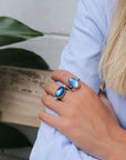 Person wearing two blue rings with a blue and blurred background