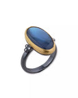 Ring with blue stone and gold band on a white background angled view