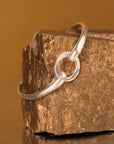silver circle cuff on a rock with an orange background