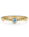 Gold ring with a blue gemstone on a white background