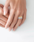 Close-up of a hand wearing a gold and silver ring on a light background