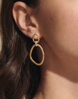 Gold earring worn by a person with brown hair.