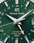 Close-up perspective shot of the Grand Seiko SBGJ251 watch face, highlighting the fine, organic forest-green dial texture, the multi-faceted silver indexes, the 24-hour scale tracking ring, and the rose gold GMT hand.