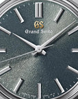 Detailed close-up perspective view of the Grand Seiko SBGW311 dial face, highlighting the dense, radiating ridges of the signature Mt. Iwate texture in its unique rainy-season olive green color, contrasted by high-polish diamond-cut hands and index markers.