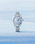 Silver grand seiko watch with blue dial on a light blue snowy gradient background