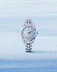 Silver grand seiko watch with blue dial on a light blue snowy gradient background