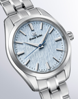 Silver watch with a light blue face on a light gray background angled