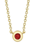 A front view of the Shy Creation Bailey Ruby Bezel Necklace (Style SC55026481) showcasing a dainty round natural red ruby inside a smooth 14k yellow gold bezel pendant, suspended from a fine matching gold cable chain on a crisp white background.