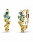 A gold huggie hoop earring featuring a row of small round-cut gemstones in green, yellow, and peach tones, set against a clean white background.