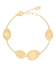 Gold bracelet with oval textured stations on a light white background