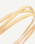 Close-up of gold ribbon bracelet on a light gray background