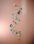 Delicate gold bracelet with blue gemstones on a gradient pink background