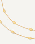 Gold necklace with small beads on a light gray background close up