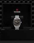 Tudor watch in a black display case with a checkered pattern background