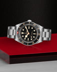 Silver watch with black dial on a red platform against a dark background