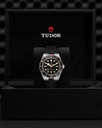 Tudor watch in a black display case with a dark textured background