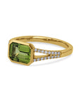 side view of yellow gold ring with green center and diamonds on a white background