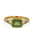 yellow gold ring with a green bezel center and embedded diamonds on a white background
