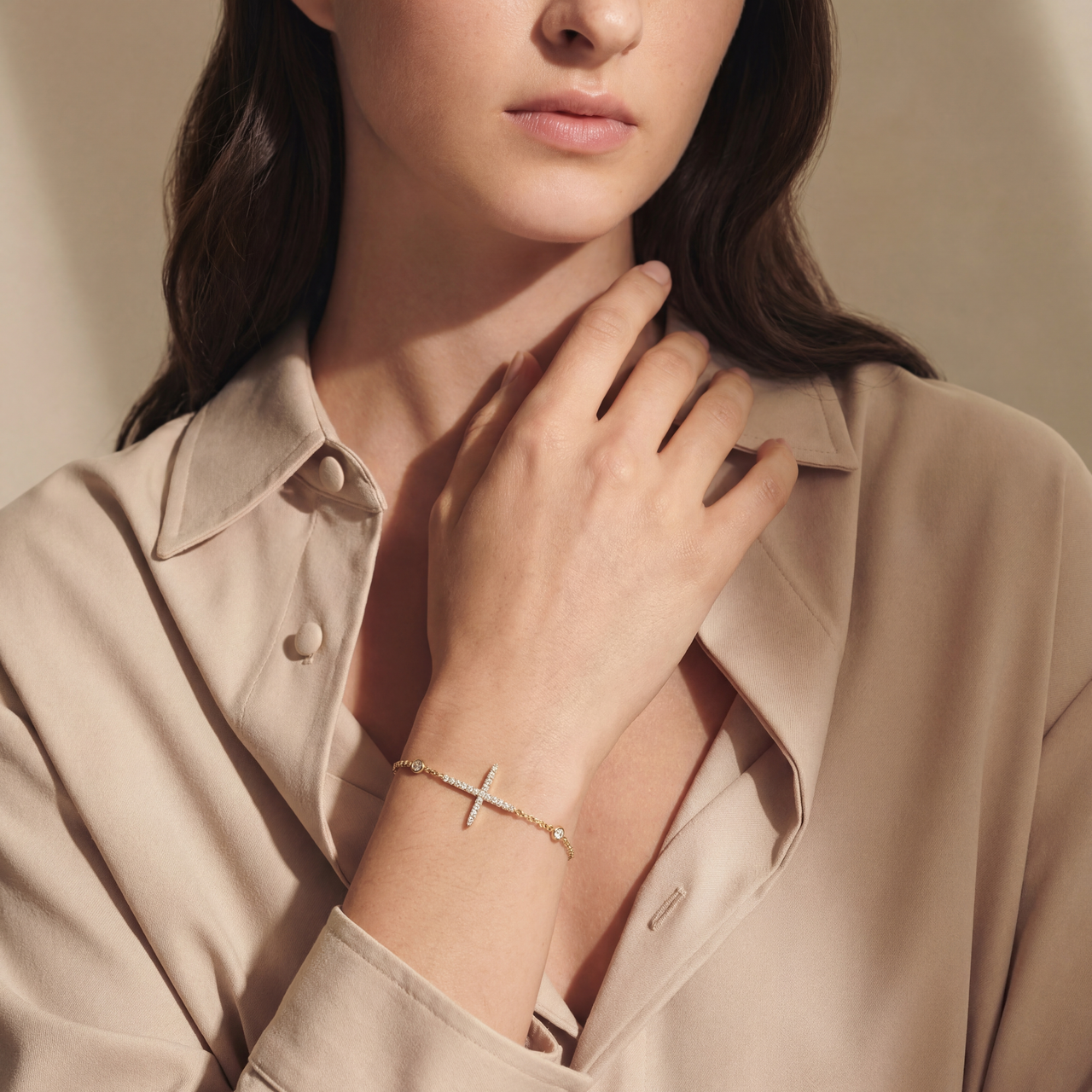 Woman wearing a beige shirt and gold bracelet, with a neutral background
