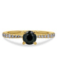 Gold ring with a dark gemstone and diamond-studded band on a white background