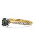 Gold ring with a green gemstone and smaller diamonds on a white background