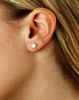 A close-up of a person's ear wearing a small gold star stud earring.