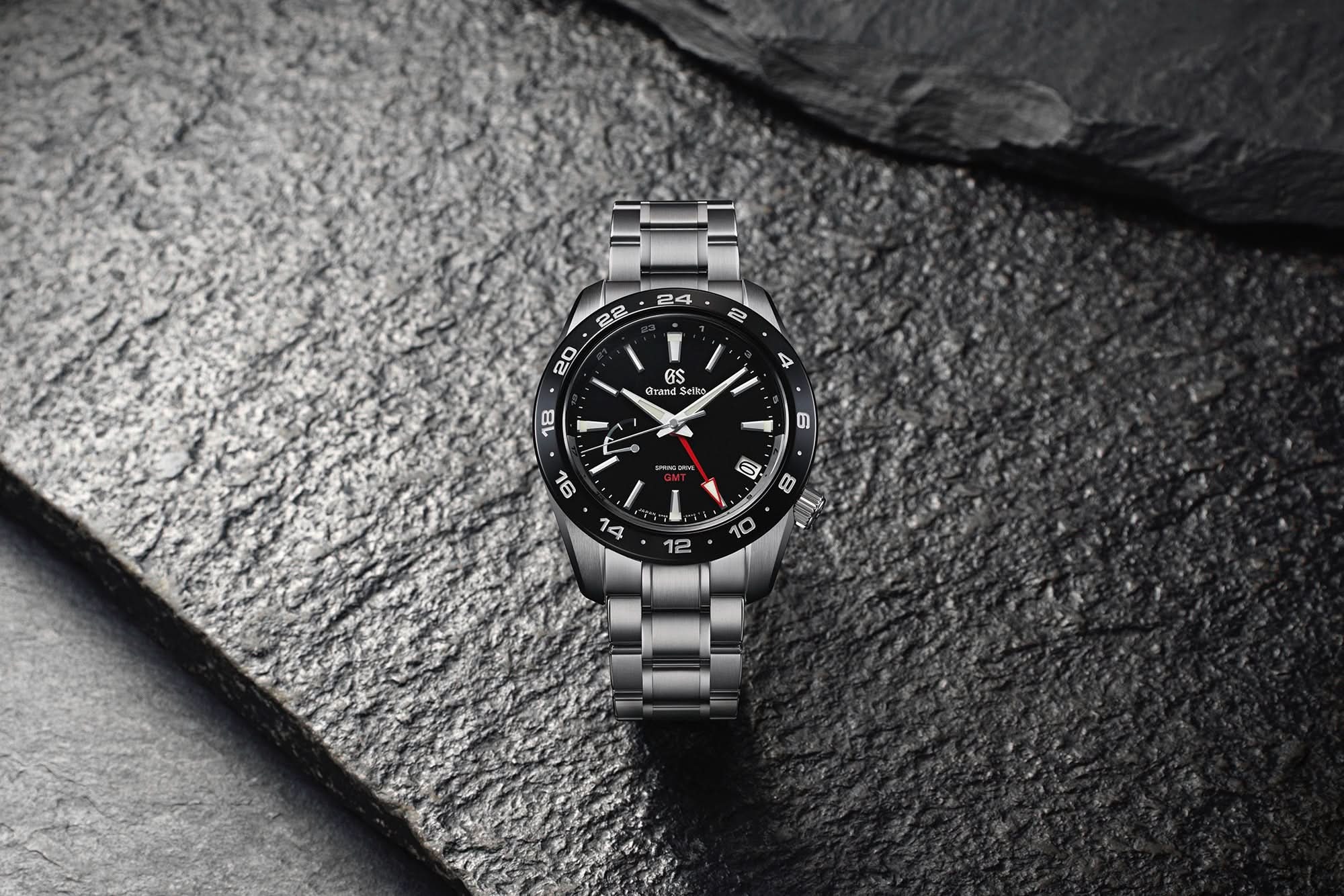 Silver watch with black face on a textured stone surface