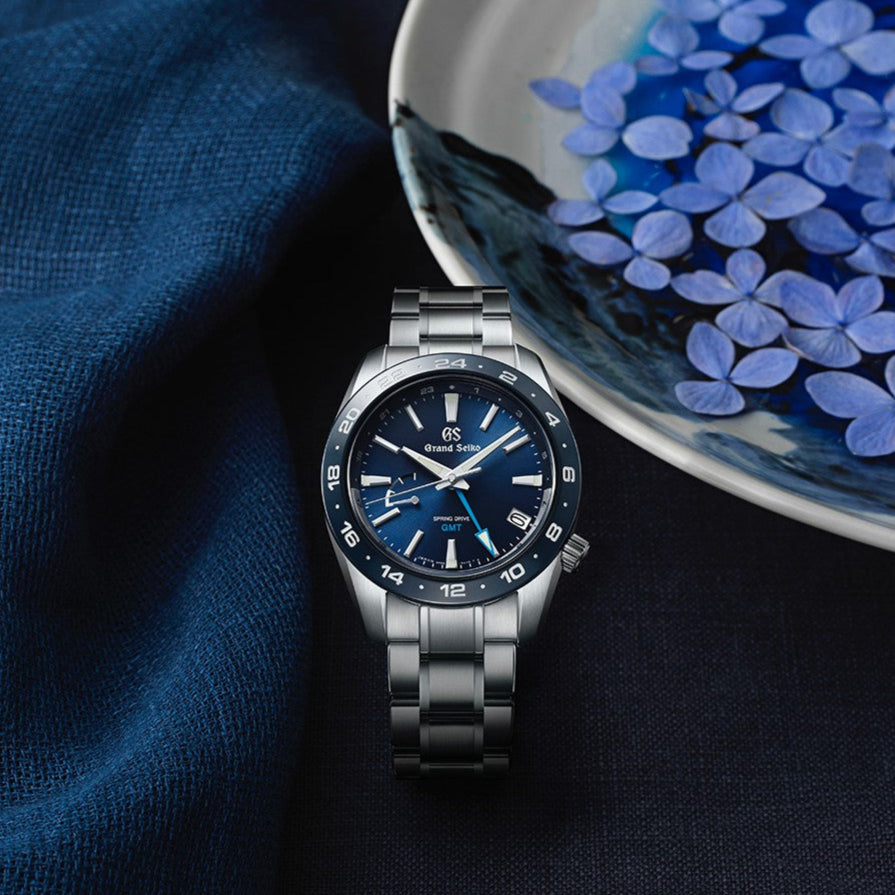 Silver watch with blue face on a dark fabric background