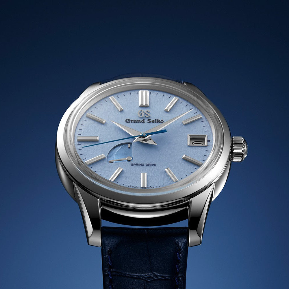 Luxury watch with blue face and dark blue strap on a gradient blue background