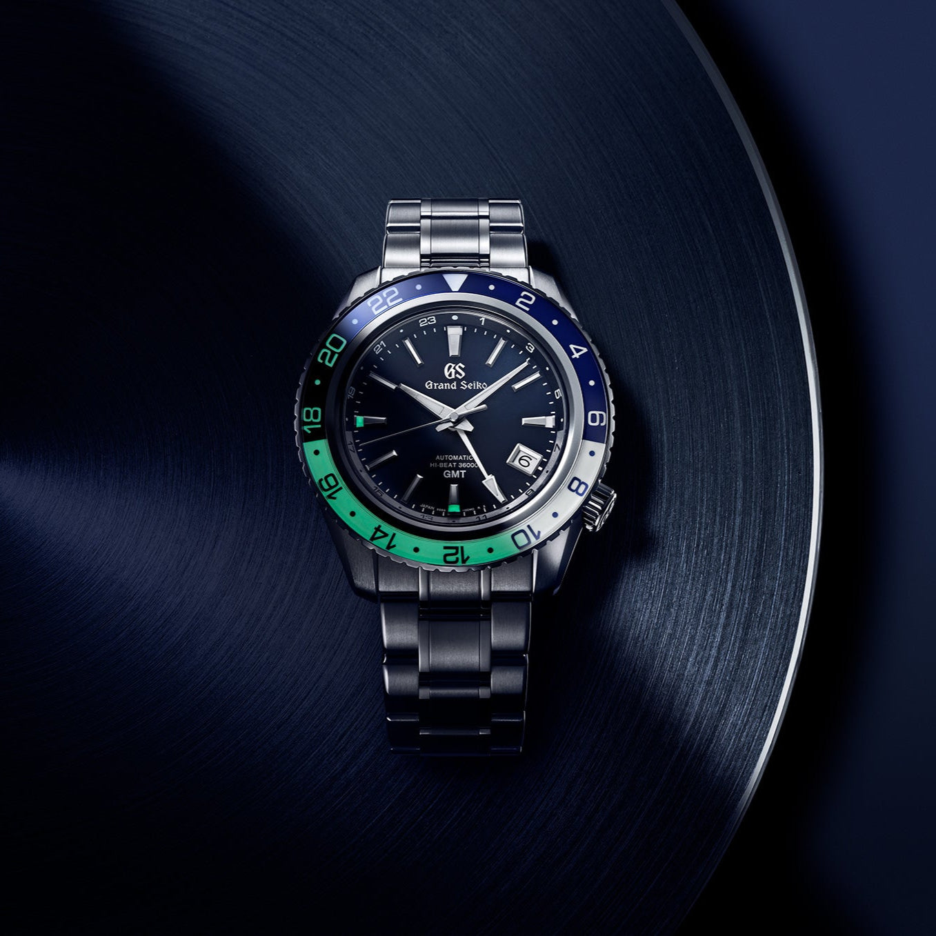 Luxury watch with a dark face and colorful bezel on a dark background