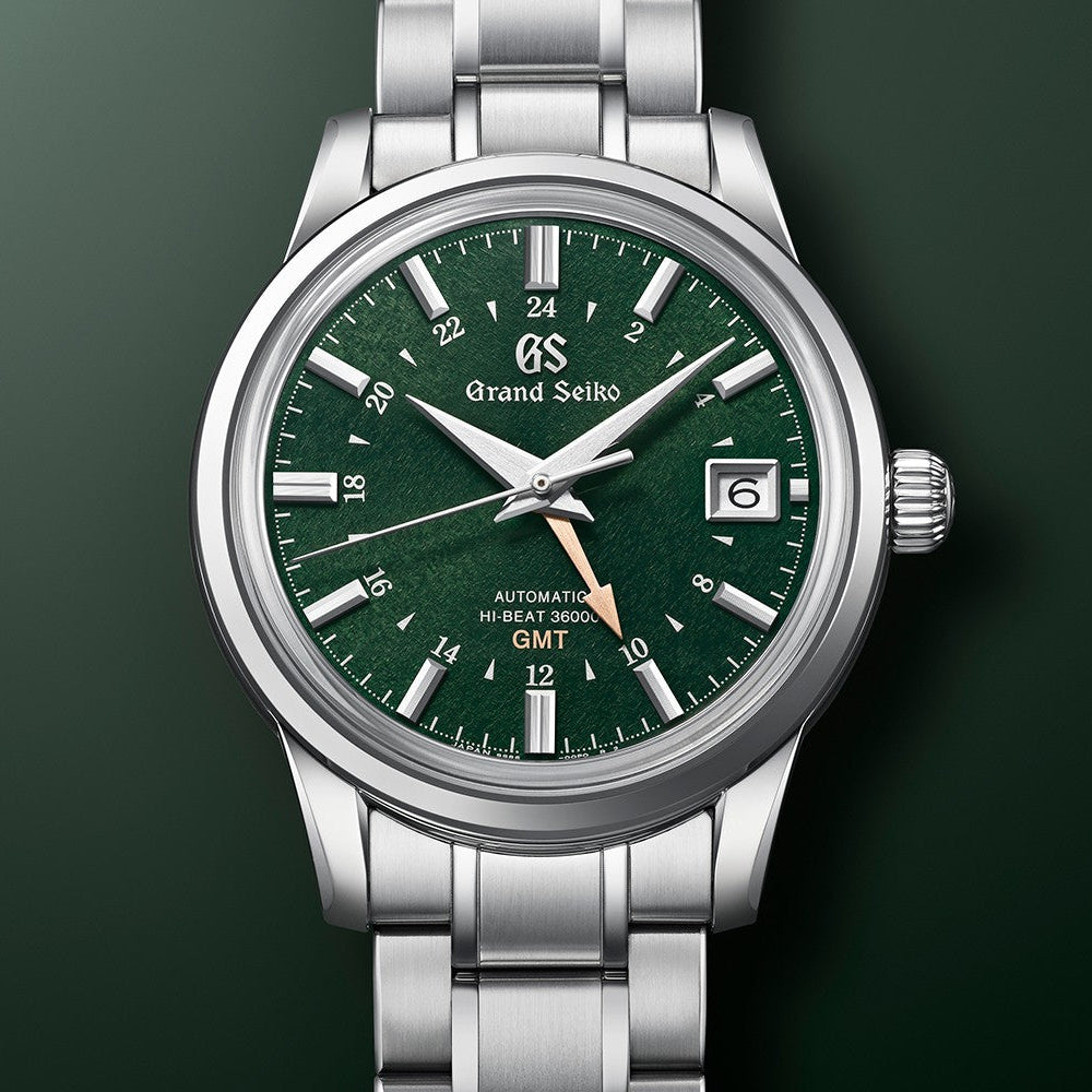 Grand Seiko watch with green dial and silver bracelet on a dark background