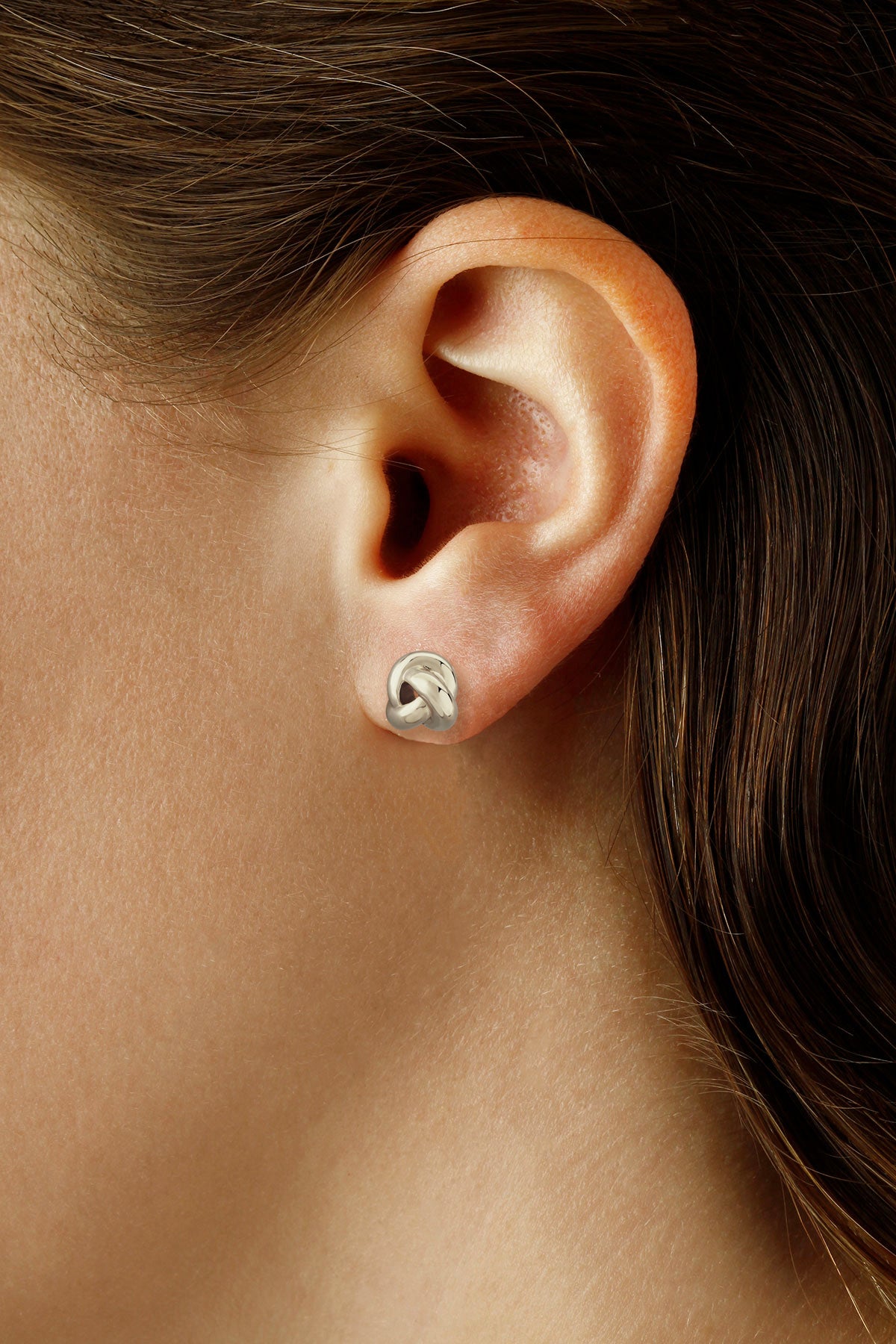 Close-up of an ear wearing a silver twisted stud earring.