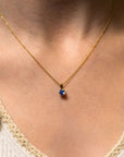 a blue tanzanite pendant on a gold chain worn by a person close-up view.