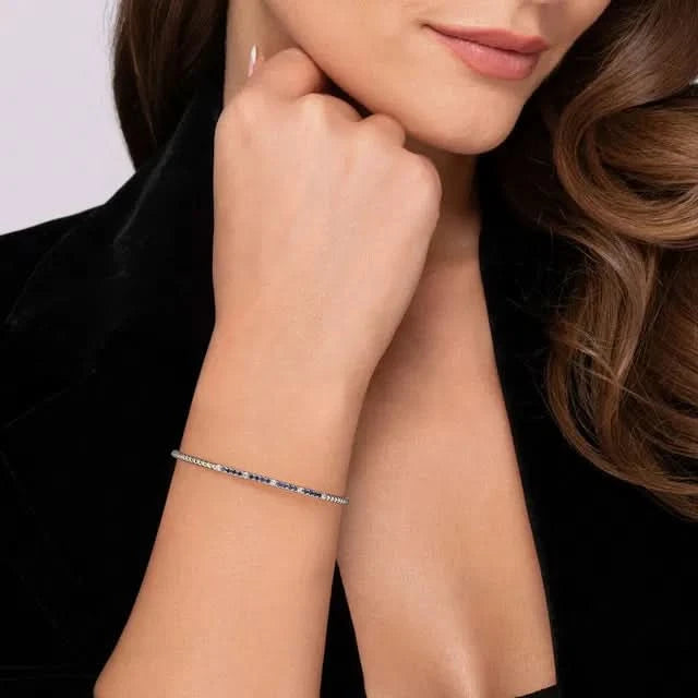 Woman wearing a white and blue bracelet on her wrist with a plain background