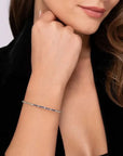 Woman wearing a white and blue bracelet on her wrist with a plain background