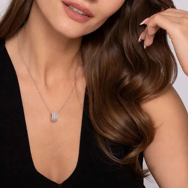 Woman wearing a white gold necklace with a square pendant against a neutral background