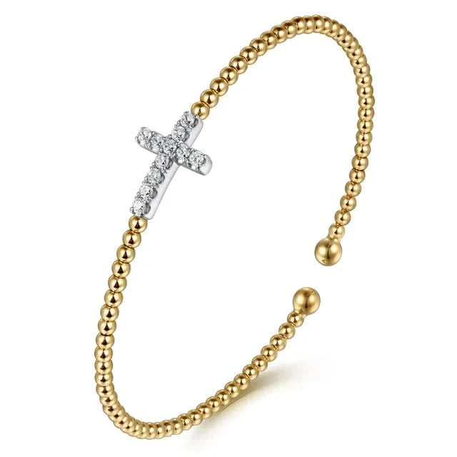 Gold beaded bracelet with a white gold cross charm on a white background