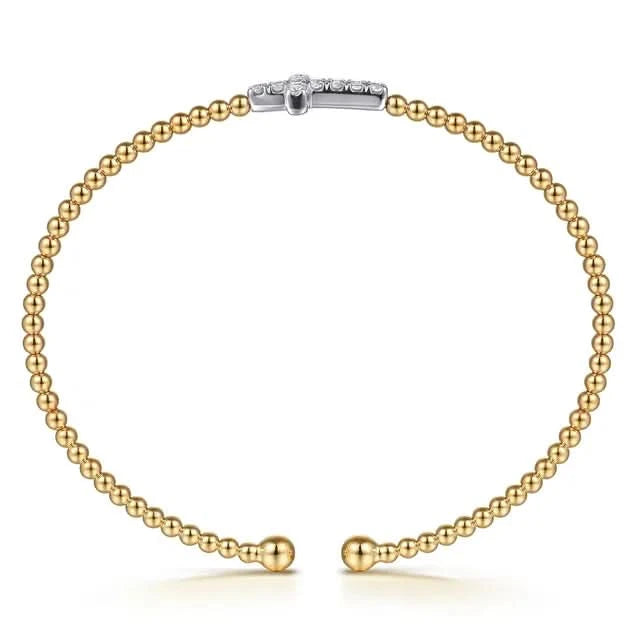 Gold beaded bracelet with a white gold cross on a white background side view