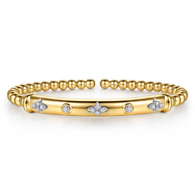 A gold bangle bracelet featuring a central bar adorned with small diamond clusters and circular diamond accents, flanked by a beaded gold band, shown on a clean white background.