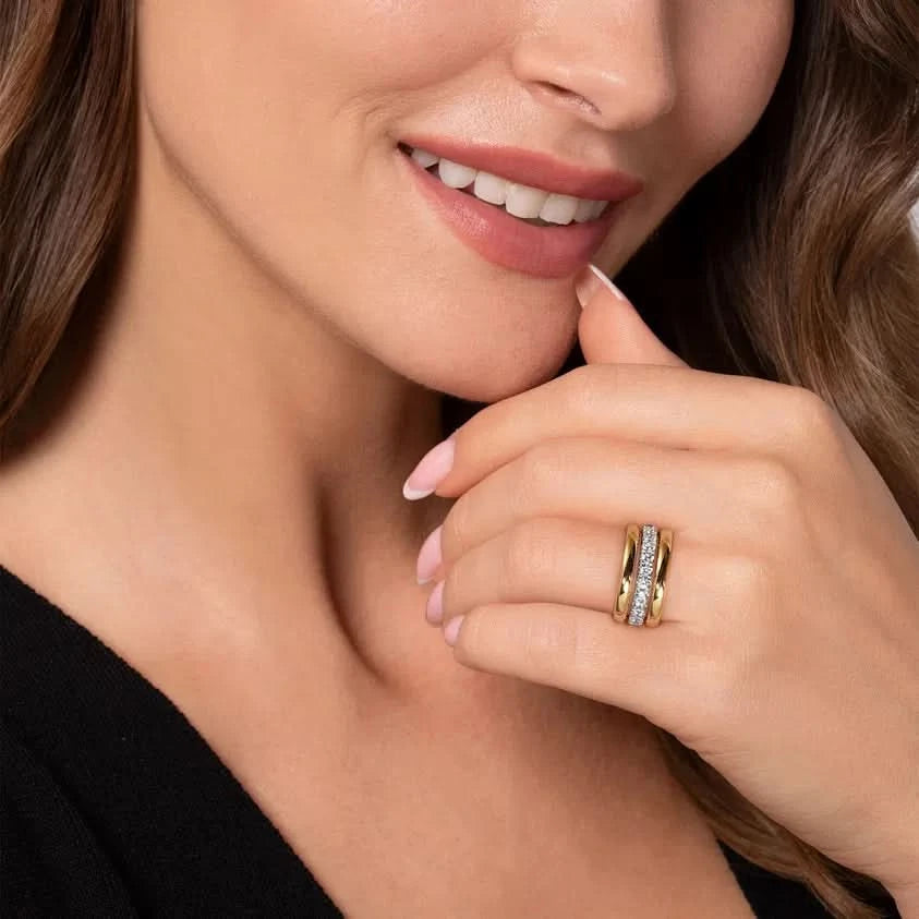 Close-up of a woman's hand wearing a gold ring with a diamond, against a neutral background.