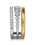 A three stacked rings shown from the side on a white background. two are white gold with a pavé diamond band, and the other is plain yellow gold side view