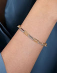 Gold bracelet with diamonds on a person's wrist against a dark blue background
