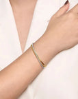 Gold bracelet on a person's wrist against a white background