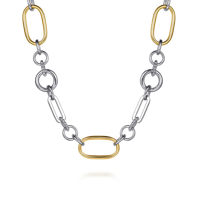 A two-tone chain necklace featuring polished silver-colored round and elongated links, accented by three gold-colored oval links, displayed on a clean white background. close up 