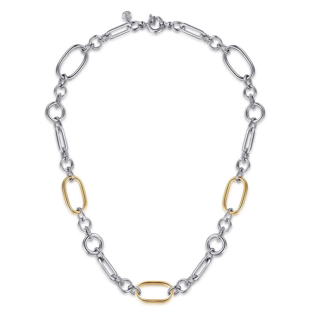 A two-tone chain link necklace featuring silver-toned oval and elongated links, accented by three polished gold-toned oval links, displayed on a clean white background.