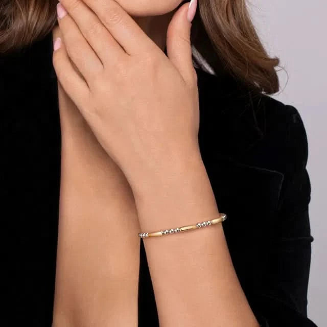 Gold and silver bracelet on a person's wrist with a neutral background